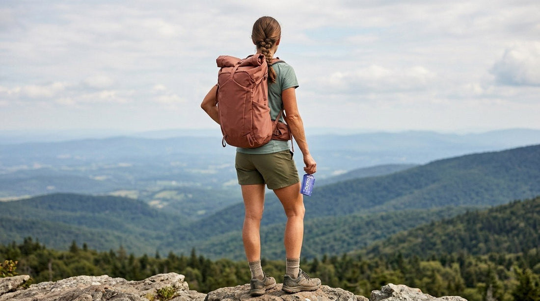 Backpacker at a mountain overlook holding a Huma Blueberries gel