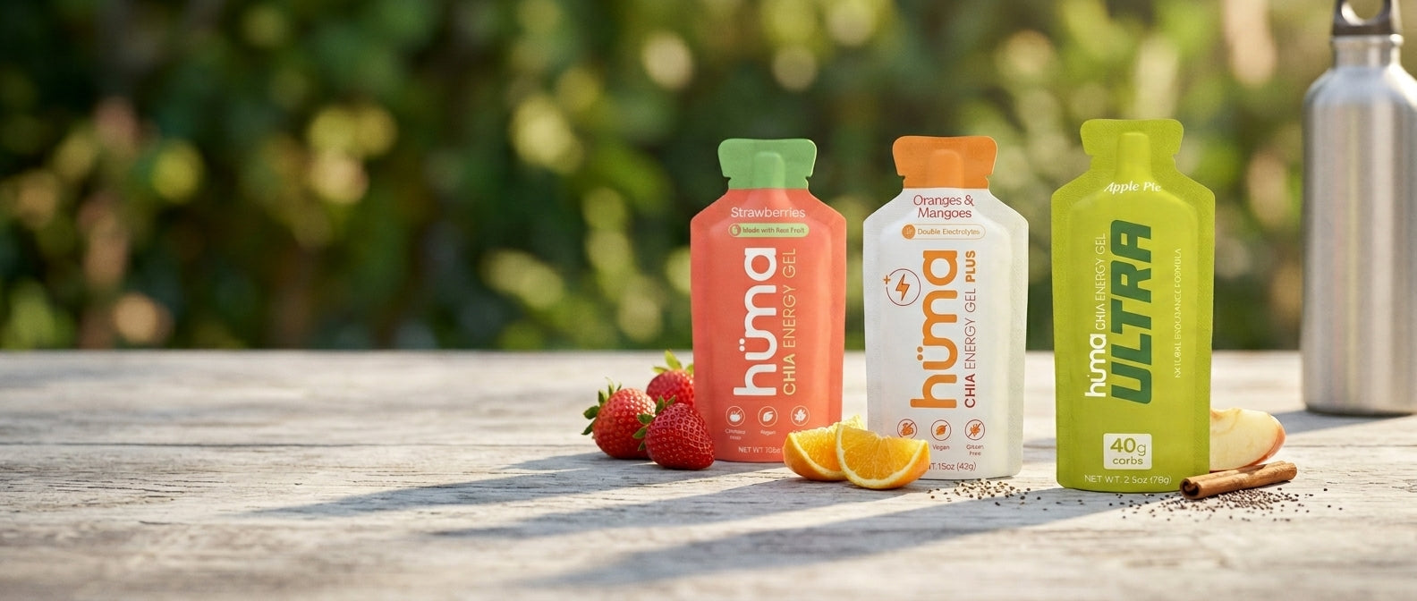 Hüma gels - Original Strawberries, PLUS Oranges & Mangoes, and Ultra Apple Pie - with real fruit and chia on a sunlit table.
